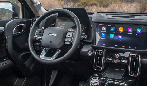 Vista interior del tablero de conductor de Haval Dargo con pantalla táctil, tacómetro digital y volante.