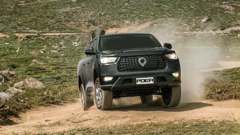 Camioneta PickUp 4x4 GWM Poer color negra siendo conducida sobre terreno sin asfaltar.